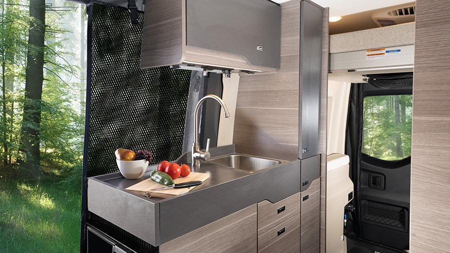 Launch 19Y Kitchen | The kitchen in the Launch 19Y has a 3-cubic-foot DC refrigerator, a portable induction cooktop, pantry space and a stainless steel sink. The side screen door has magnetic and zipper close offs to keep bugs out but let the outdoors in.