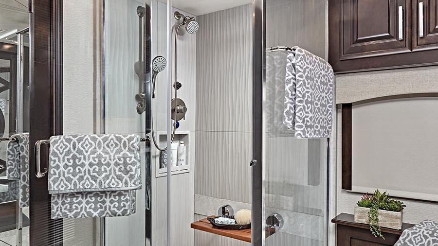 Anthem 44W Shower | The Anthem 44W features a porcelain tile shower with skylight and clear glass shower door, a teak wood shower seat, a fixed shower head and a separate hand-held spray wand and Aqua View® SHOWERMI$ER water-saving system. 