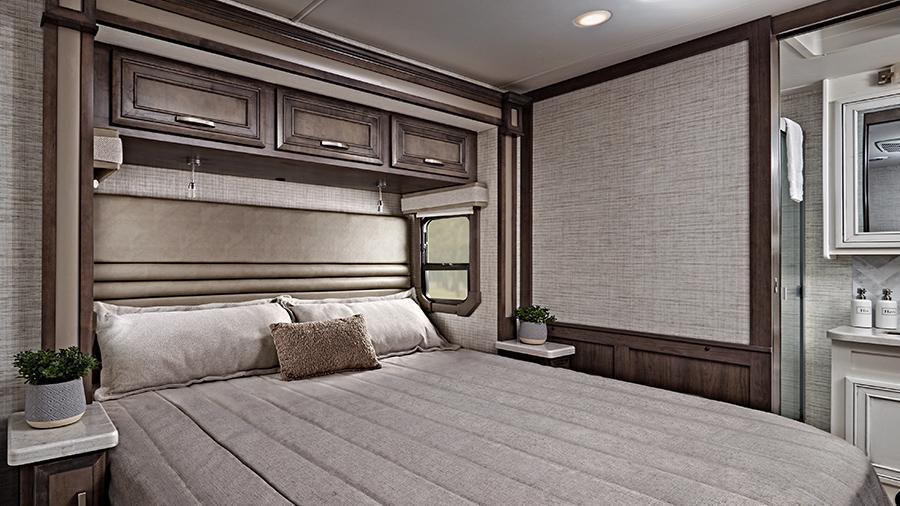 Emblem 36U Bedroom | The bedroom in the Emblem 36U features a walk-around, king size bed with bedspread and nightstands with a USB port and wireless charging in them. Select models have under-bed storage. 