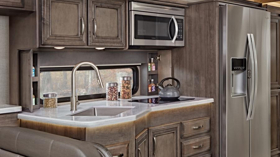 The Emblem's gourmet kitchen includes a wood-framed kitchen window with spice cabinets, LED-lit solid-surface countertops, residential refrigerator, convection microwave oven and two-burner induction cooktop. (36H Shown)