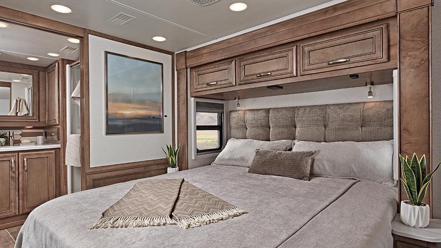 Reatta 39BH Bedroom | Warm and inviting, the Reatta 39BH bedroom has a king size pillow-top mattress on a tilt bed, nightstands, overhead storage, reading lights and a residential-style headboard.