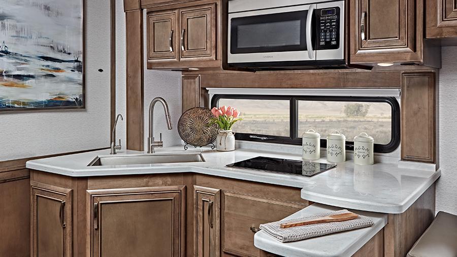 Reatta 39BH Kitchen | The Reatta kitchen has an induction cooktop, a 1.5-cubic-foot convection microwave oven, solid-surface countertops with a stainless steel sink and a stainless steel residential refrigerator (39BH Shown).  